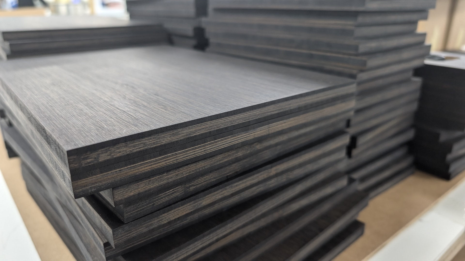 Stacked bamboo/plywood panels with visible layered edges, photographed in a workshop or material storage area — suitable for CNC routing or fabrication projects.