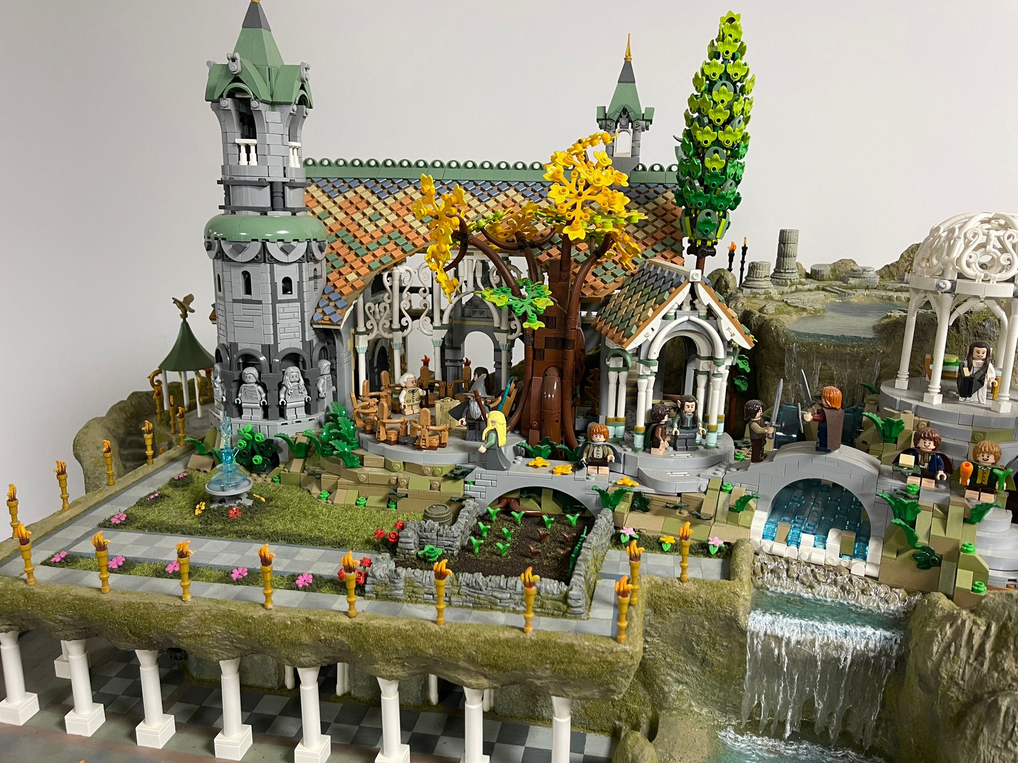 Elaborate LEGO castle diorama with a waterfall, displayed on a shelf in a home setting.