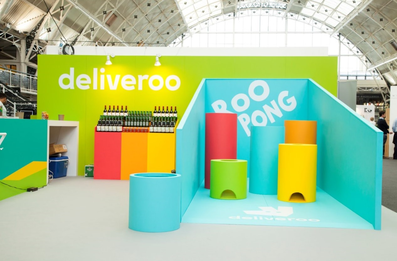 Deliveroo branded exhibition stand with colourful interactive booth and prominent branded backwall at a trade show or event.