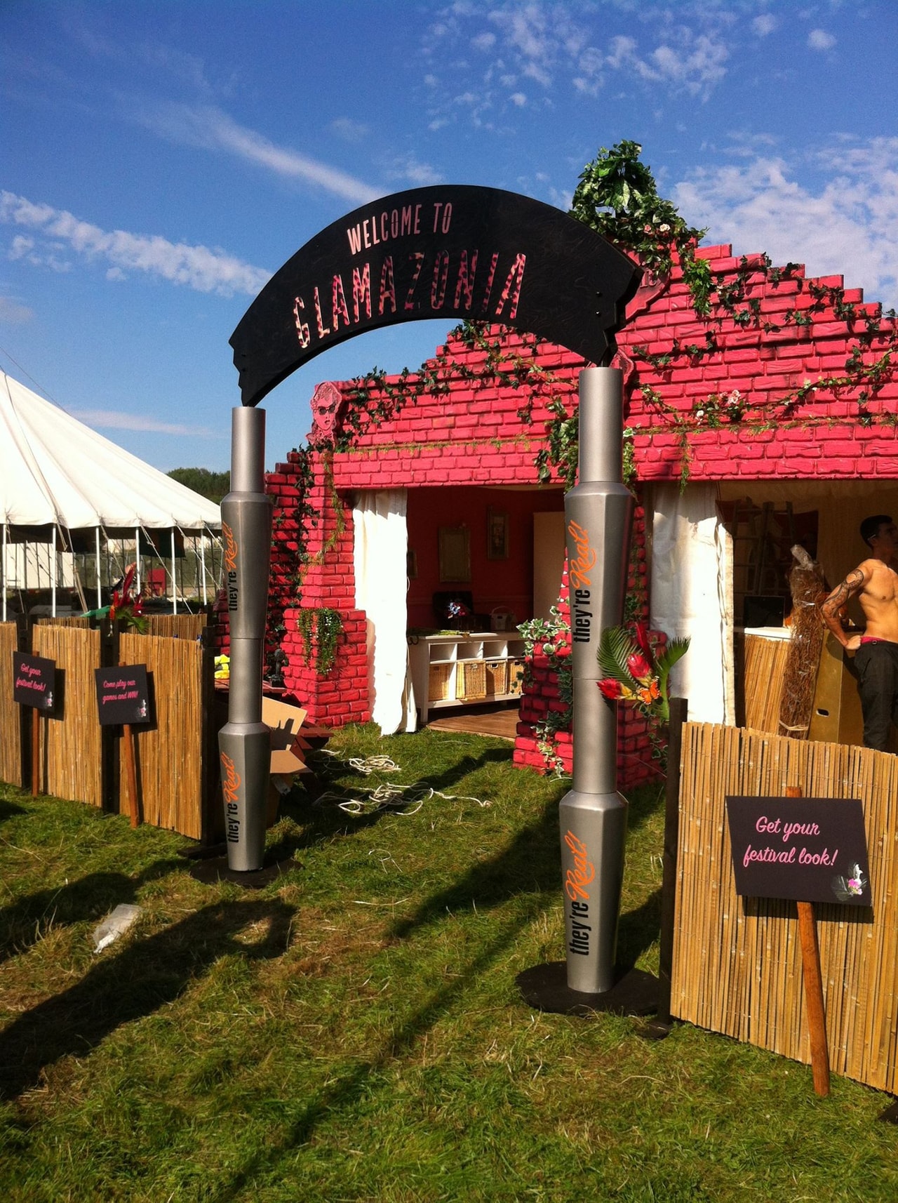 Outdoor festival installation featuring a themed entrance arch and temporary booth with branded signage and decorative columns at an event.
