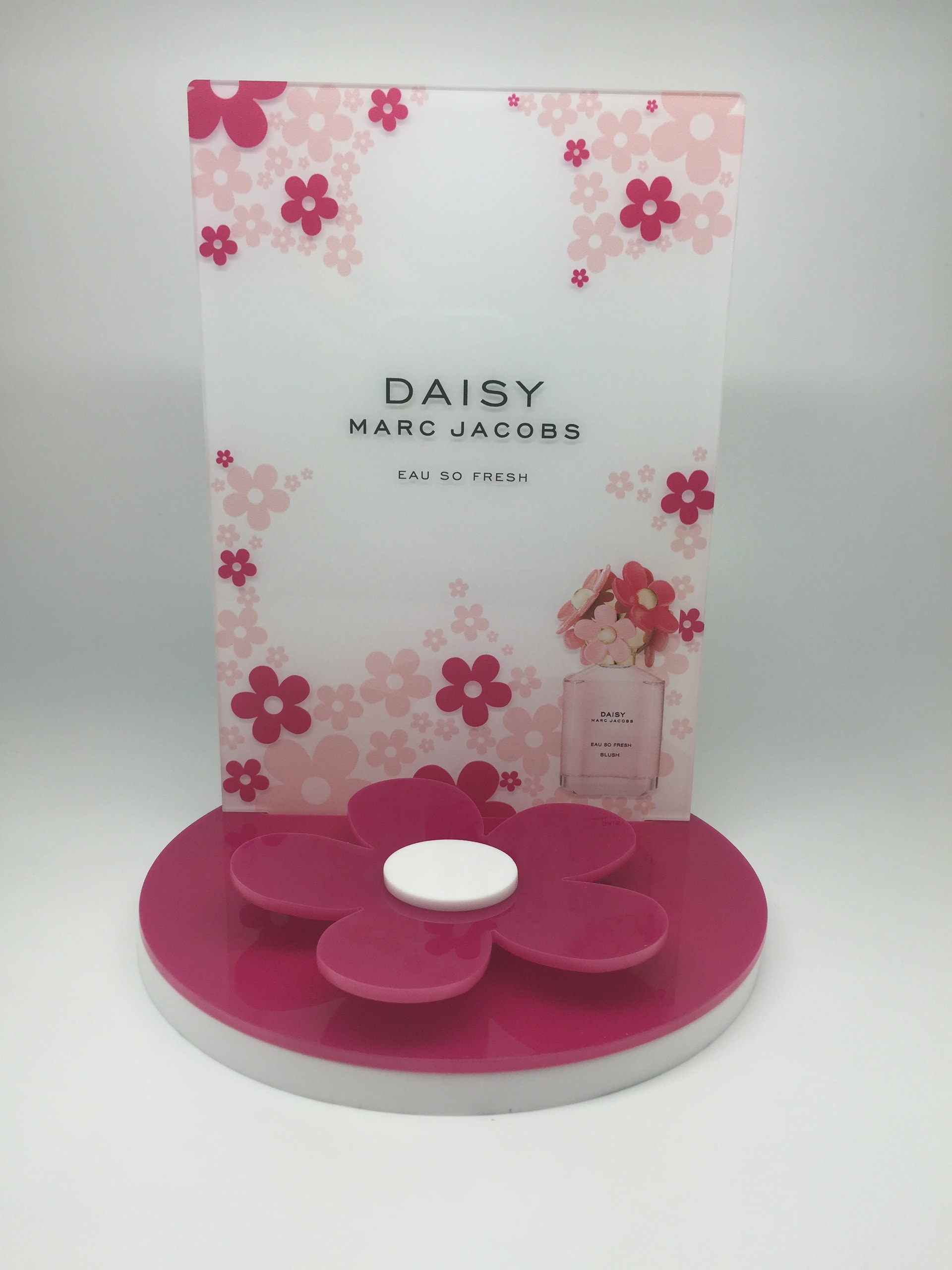 Clear acrylic point-of-sale display stand with branded graphics photographed in a studio setting.