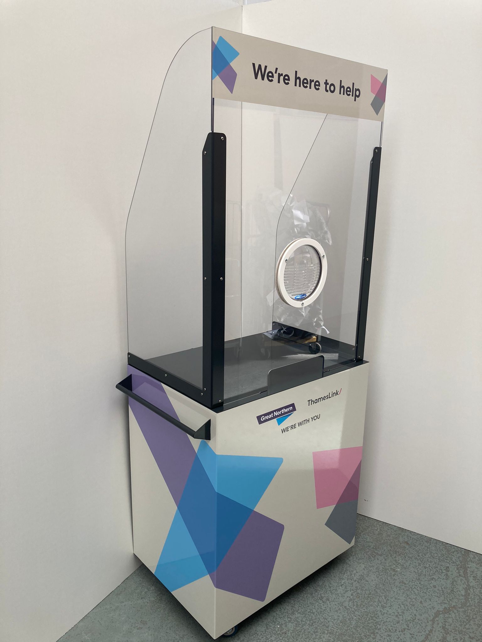 Branded acrylic protective customer service kiosk with clear screen, printed graphics and a circular pass-through port on a wheeled base, suitable for customer-facing environments.