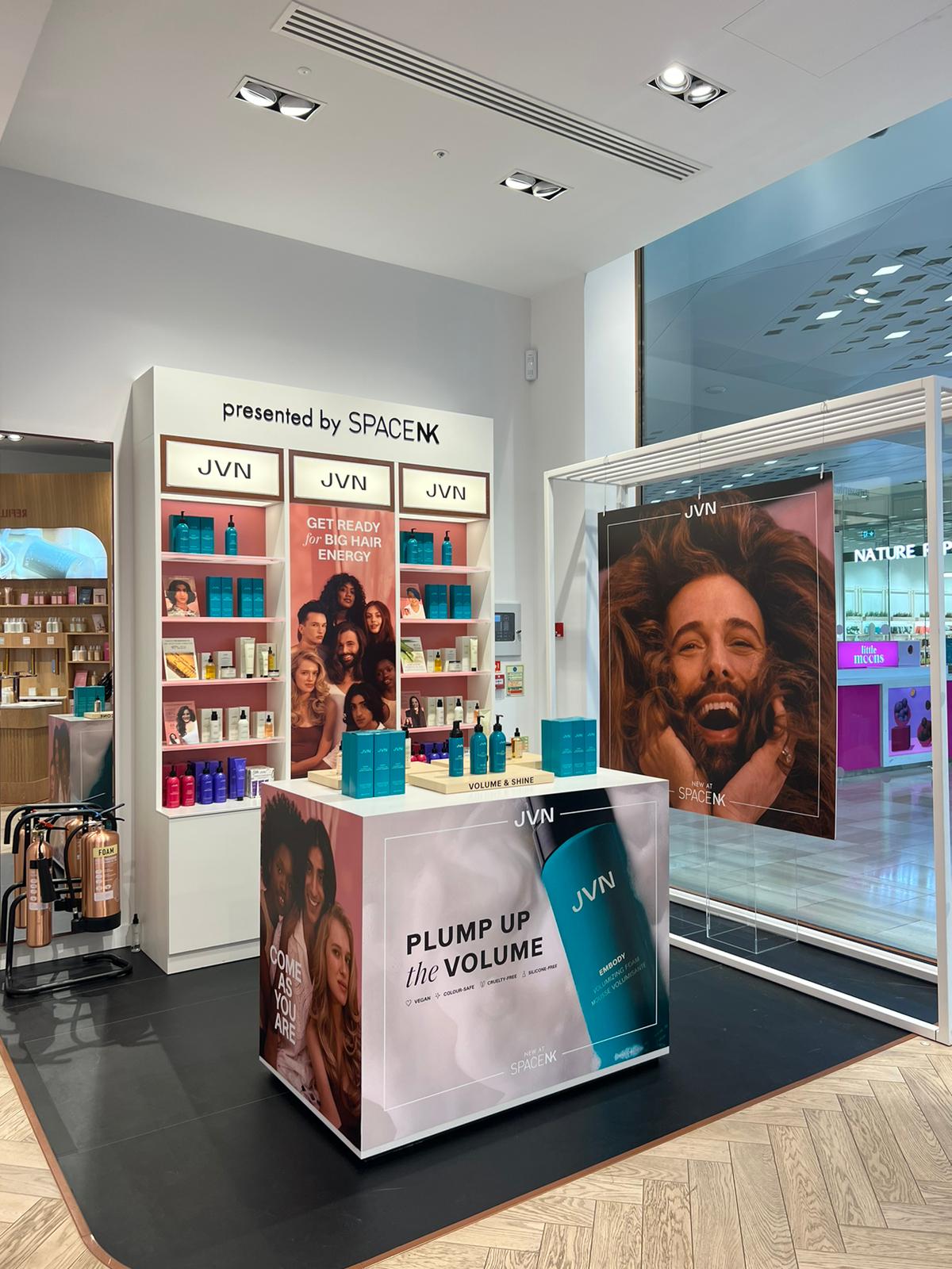 JVN x SpaceNK branded pop-up kiosk in a shopping centre featuring product shelving, countertop displays and large-format promotional graphics.