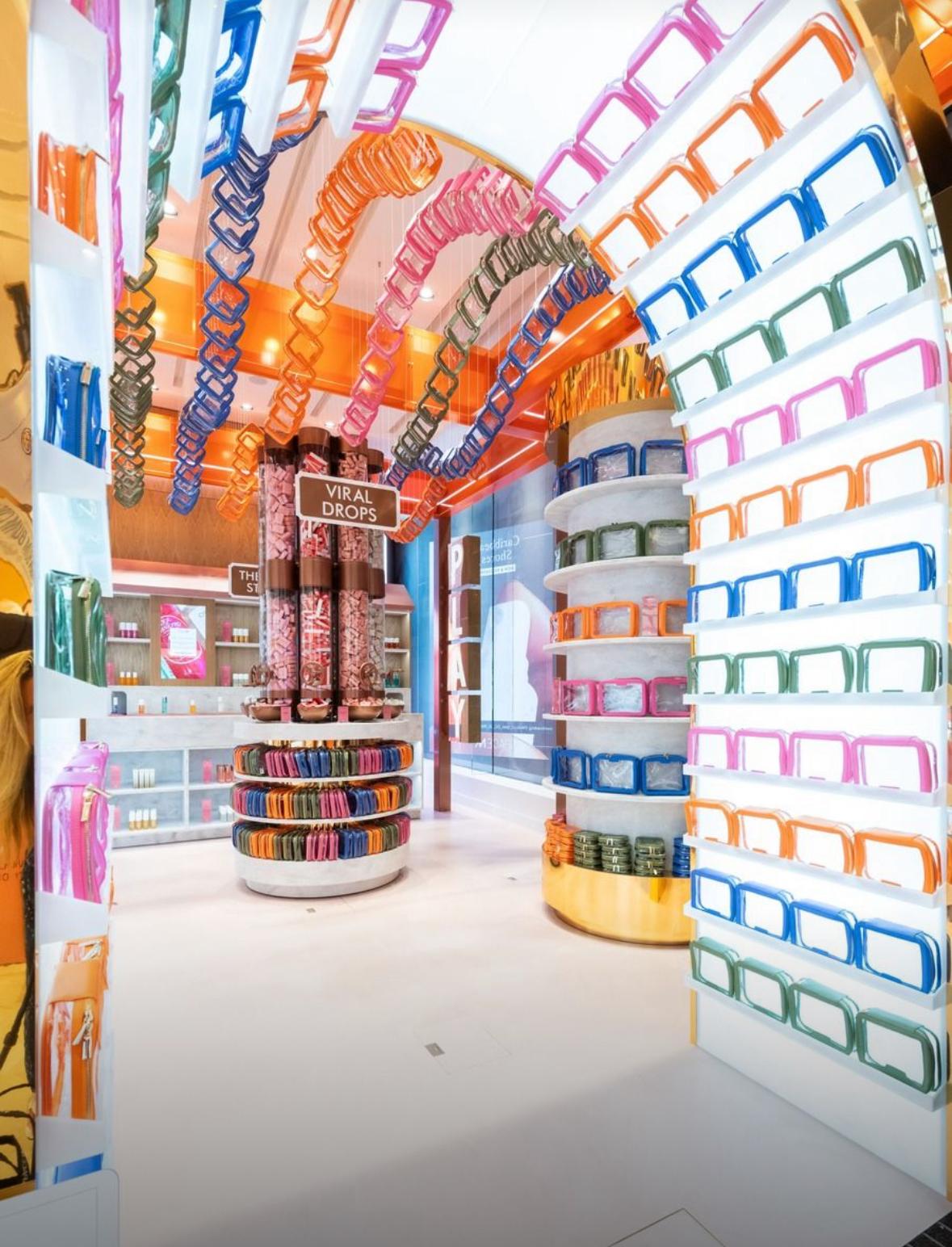 Vibrant retail store interior with colourful acrylic display fixtures, circular product towers and hanging installations showcasing small viral products and skincare displays.