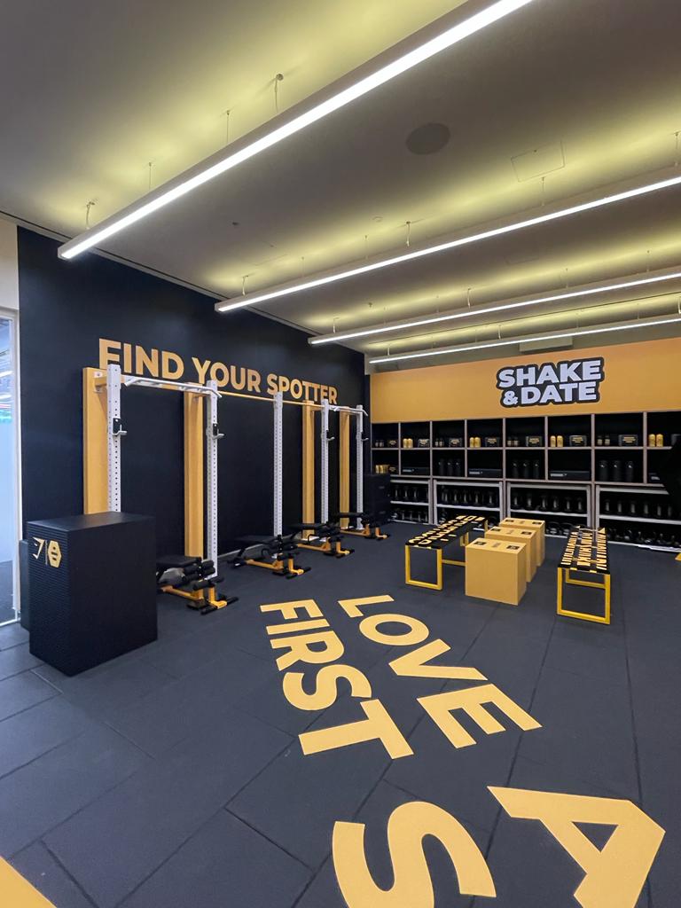Branded Gymshark retail/activation space with product shelving, gym equipment and prominent wall and floor graphics, photographed in a clean, well-lit interior.