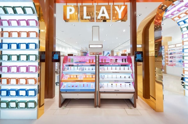 High-end Space NK cosmetics retail display featuring illuminated product counters and shelving under a prominent 'PLAY' header inside a bright store interior.