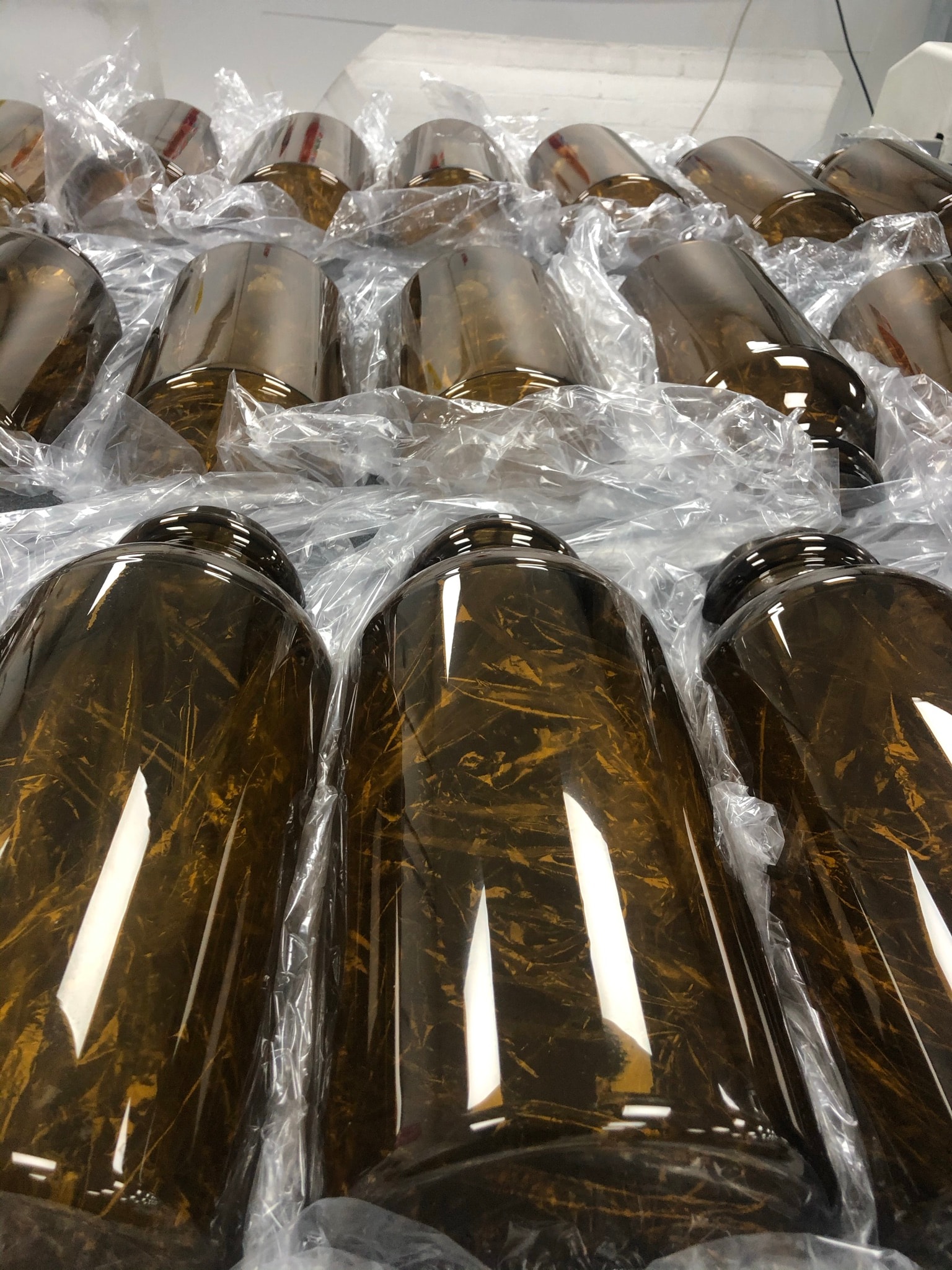 Stacked amber vacuum-formed plastic domes with decorative marbling, wrapped in protective plastic film and arranged for packing or storage.