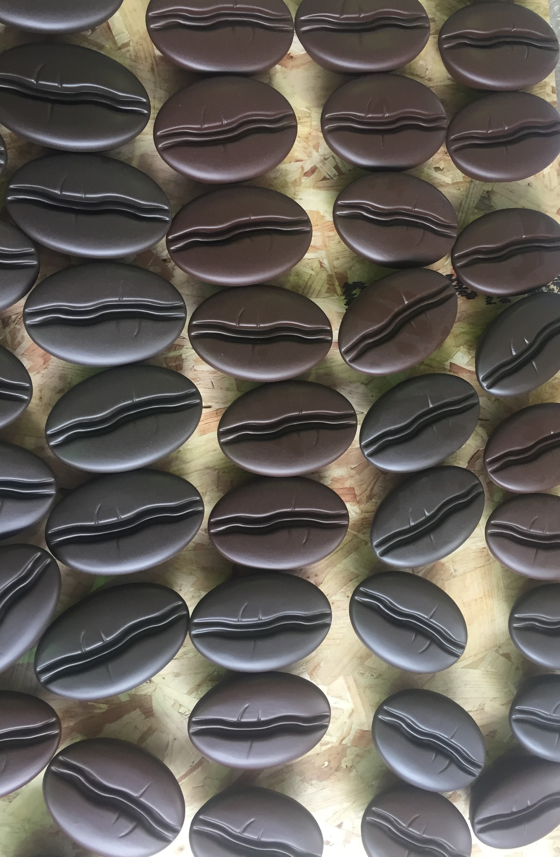 Rows of brown vacuum-formed oval shells arranged on an OSB board, likely cooled and staged for finishing.
