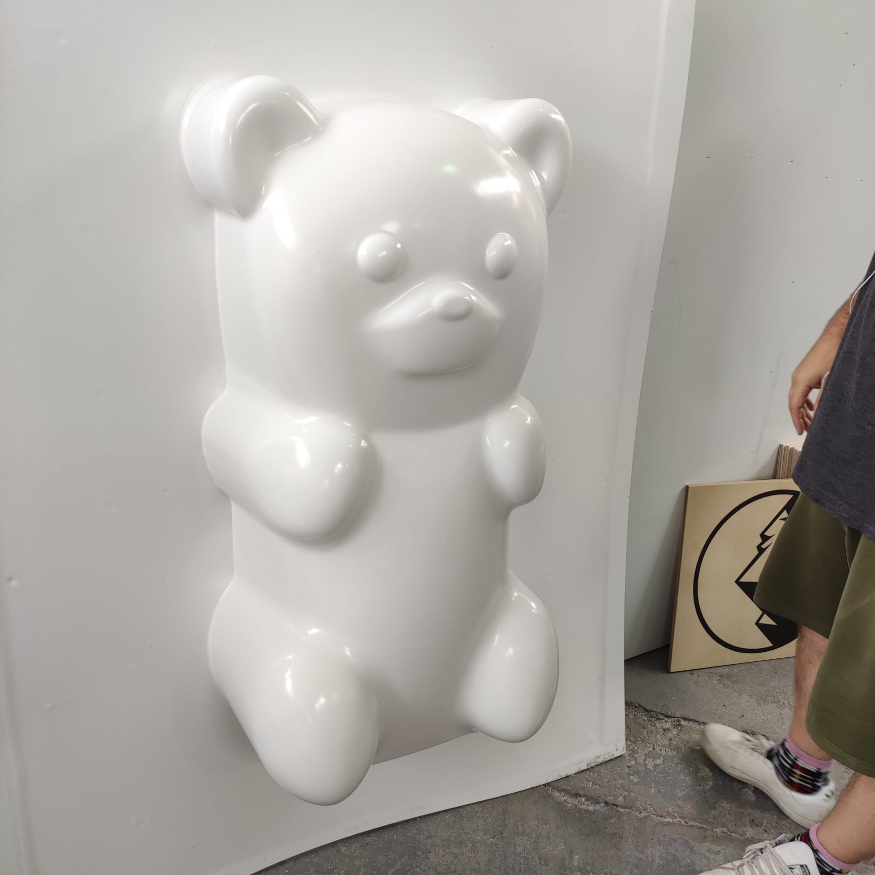 Glossy white vacuum-formed bear-shaped plastic shell photographed in a workshop, showing a finished formed panel ready for use as a display or fixture.
