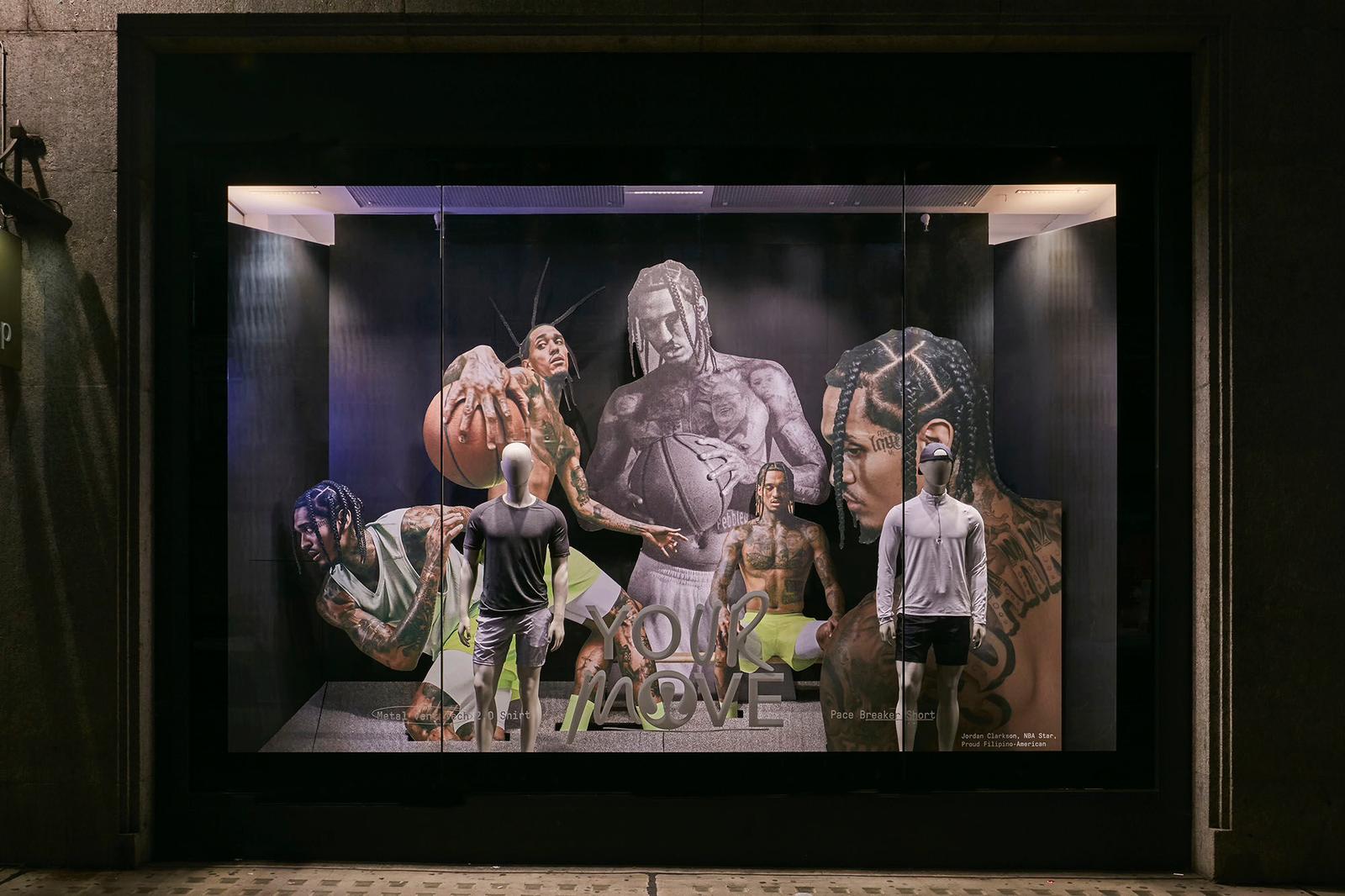 Shop window display featuring large-format printed backdrop and mannequins in a retail storefront, photographed at night with lit display case.