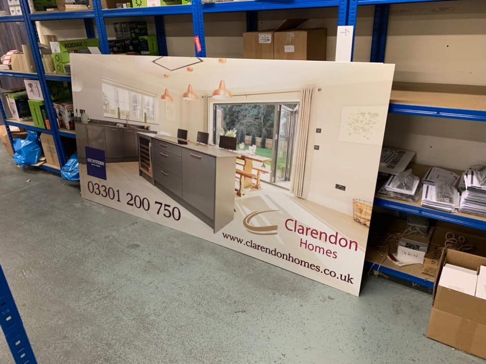Large-format printed hoarding panel for Clarendon Homes shown in a workshop, ready for site installation